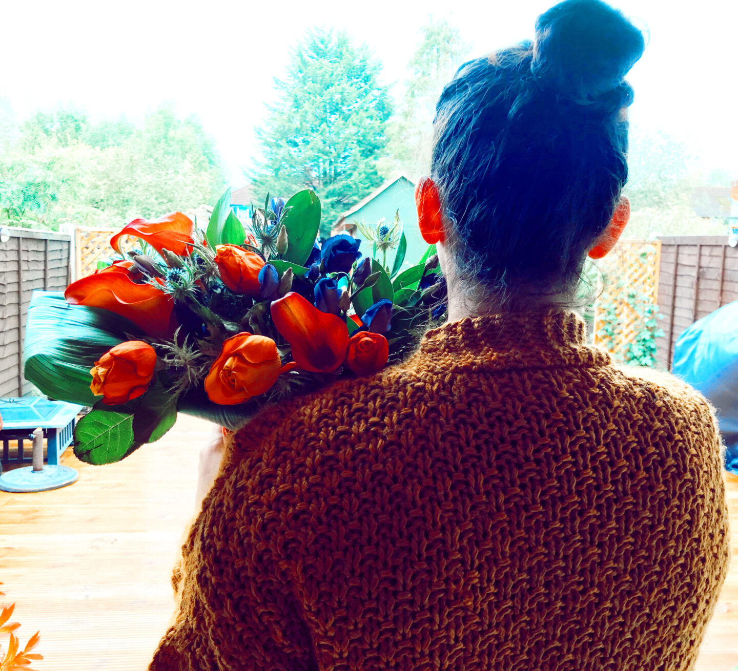 girl looks out of window with flowers in her hand