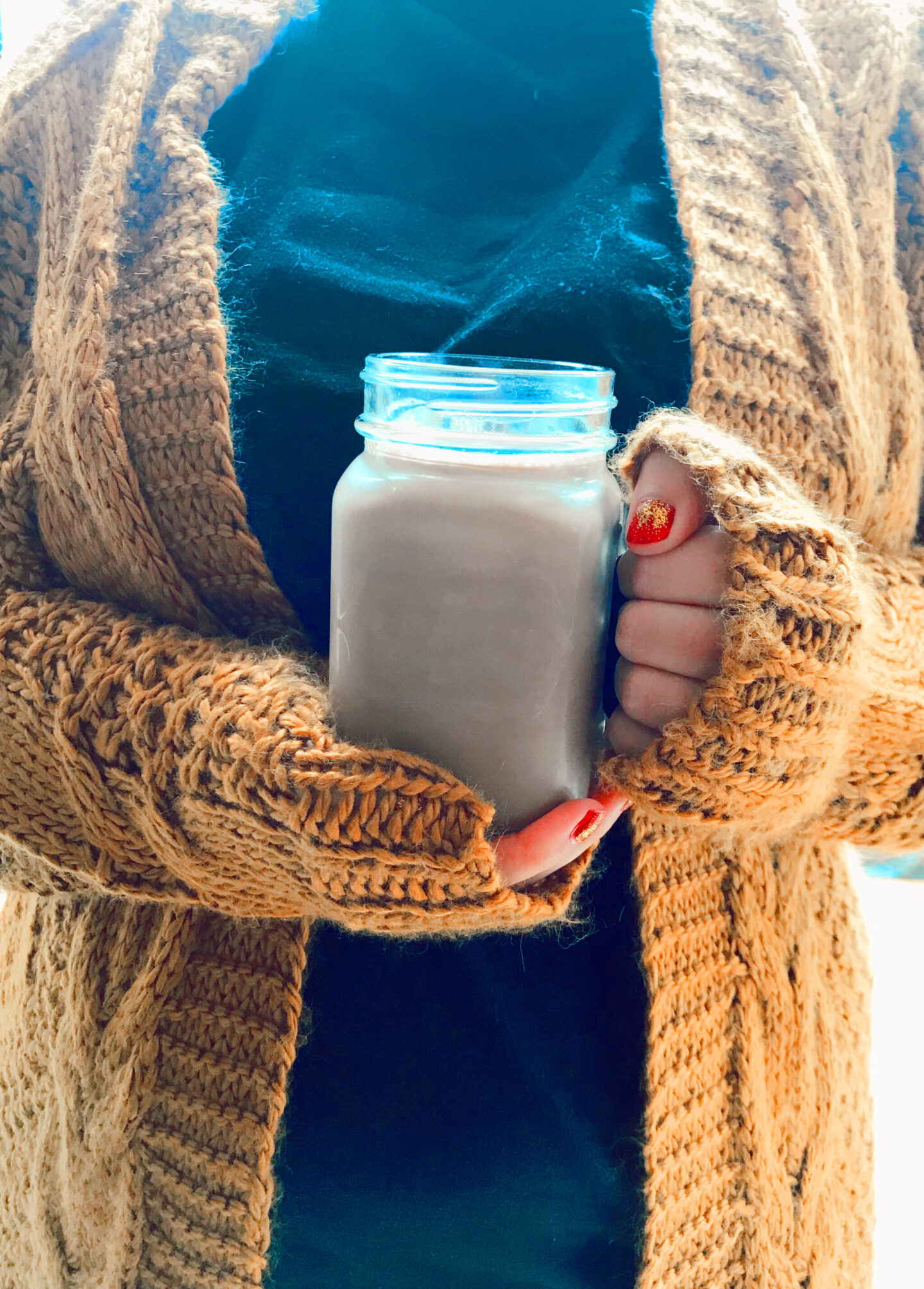 a female wears an orange cardigan and holds a chocolate milkshake
