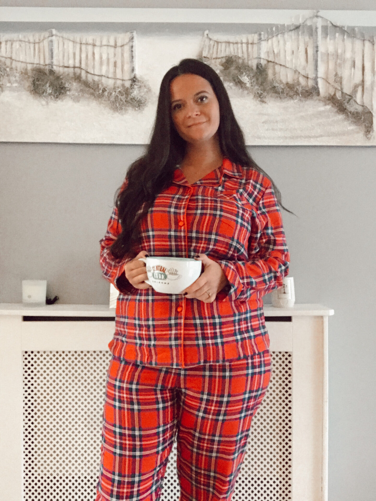 a female wears tartan pyjamas and drinks a cup of tea